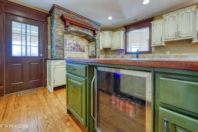 kitchen featuring visible vents, wine cooler, recessed lighting, light wood-style floors, and a sink