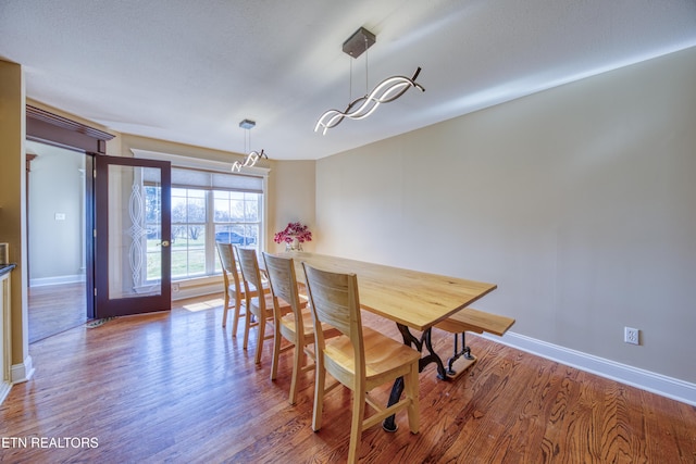 dining room featuring baseboards, a notable chandelier, and wood finished floors