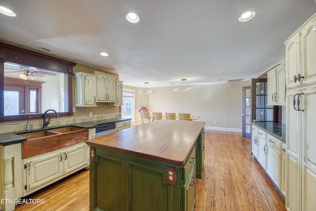 kitchen featuring a kitchen island, a sink, light wood-style floors, dishwasher, and butcher block counters