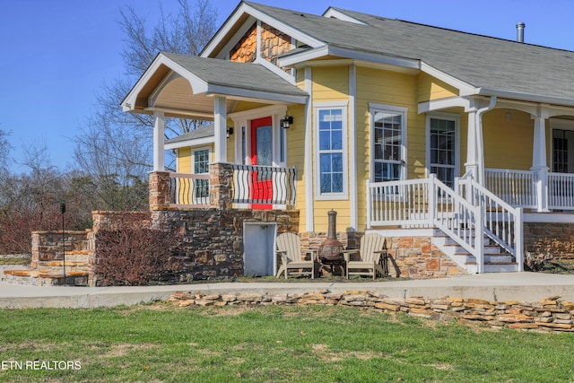 view of front of home featuring stone siding, a porch, and a shingled roof