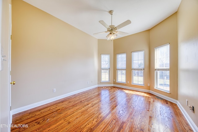 empty room featuring baseboards, wood finished floors, visible vents, and ceiling fan