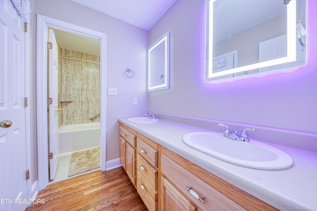 bathroom featuring double vanity, wood finished floors,  shower combination, and a sink