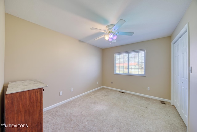 unfurnished bedroom featuring a ceiling fan, baseboards, visible vents, and light carpet