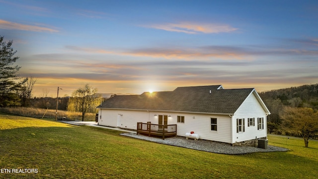 rear view of house with a yard, central air condition unit, a wooden deck, and a shingled roof