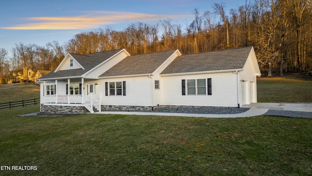 view of front of home featuring a yard, fence, covered porch, and a shingled roof