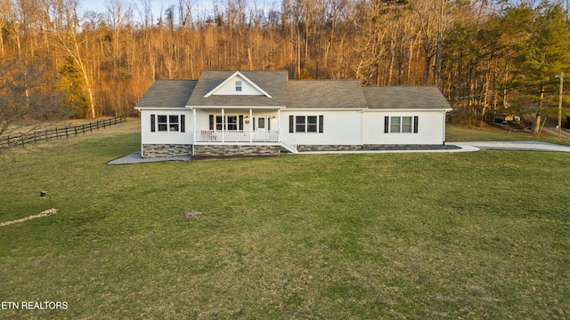 view of front facade with covered porch, a front yard, and fence