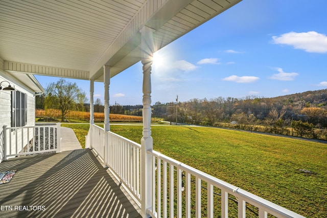 wooden terrace with a porch and a lawn