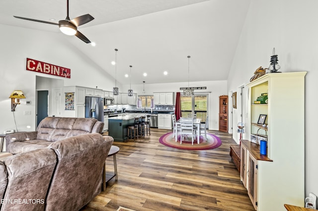 living area featuring a ceiling fan, wood finished floors, and high vaulted ceiling