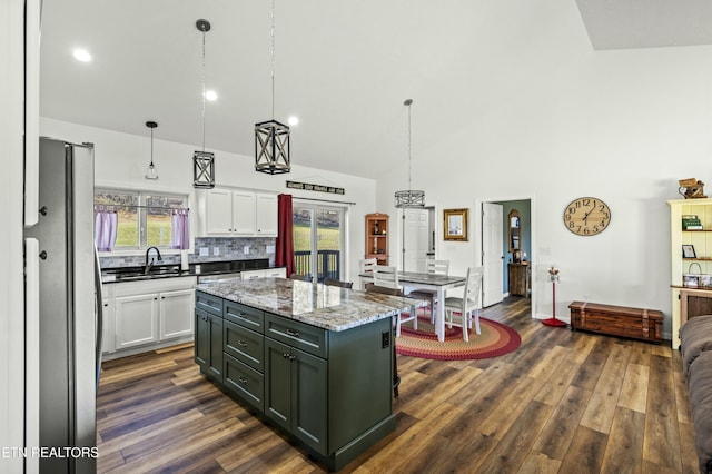 kitchen with a wealth of natural light, high vaulted ceiling, dark wood-style floors, white cabinetry, and freestanding refrigerator