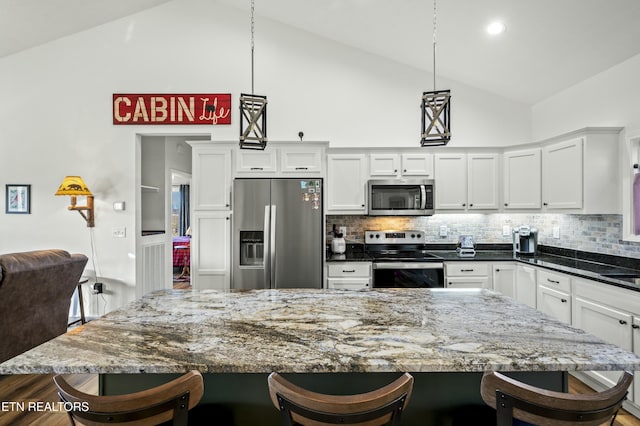 kitchen with appliances with stainless steel finishes, white cabinetry, and a kitchen bar