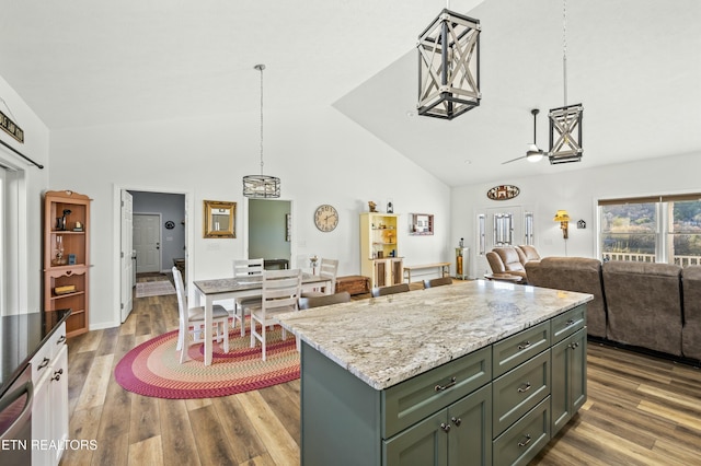 kitchen featuring a center island, open floor plan, light stone counters, wood finished floors, and hanging light fixtures