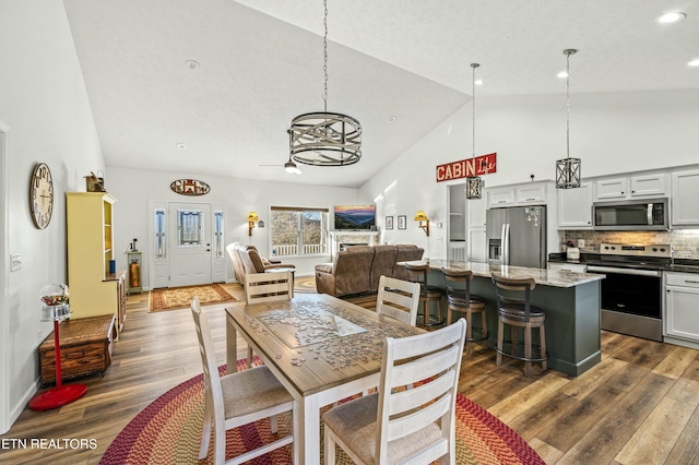 dining area with dark wood-style floors, recessed lighting, and high vaulted ceiling