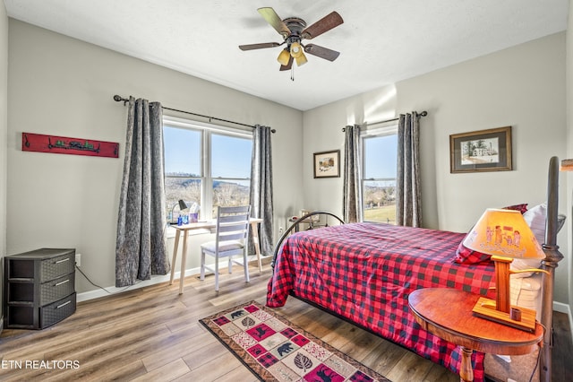 bedroom with a ceiling fan, wood finished floors, baseboards, and a textured ceiling