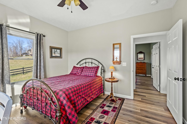 bedroom featuring baseboards, wood finished floors, and a ceiling fan