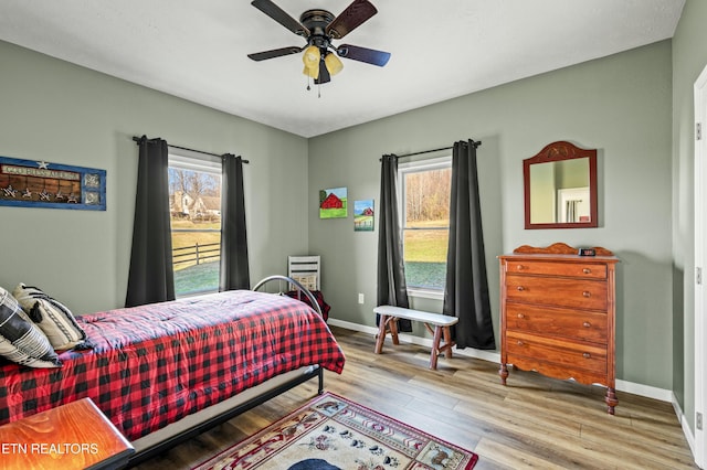 bedroom with a ceiling fan, wood finished floors, and baseboards