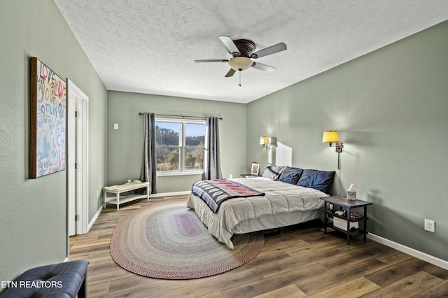 bedroom featuring wood finished floors, baseboards, ceiling fan, a textured ceiling, and a textured wall