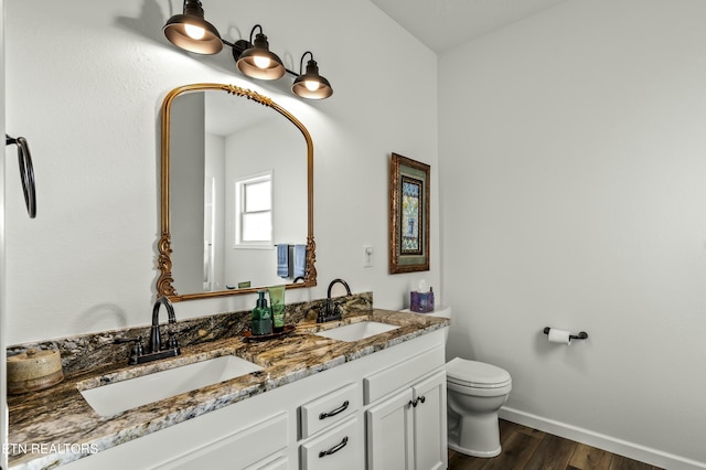 bathroom featuring toilet, wood finished floors, baseboards, and a sink