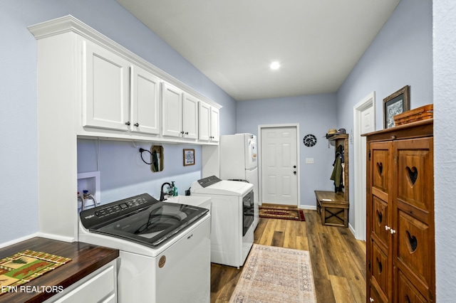 clothes washing area featuring washer and dryer, baseboards, cabinet space, and dark wood-type flooring