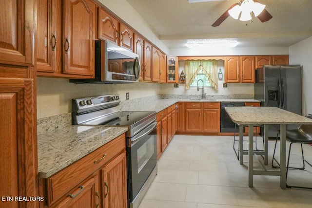 1301 Chert Pit Rd, Knoxville, TN 37923 - kitchen featuring black appliances, brown cabinetry, ceiling fan, glass insert cabinets, and light stone countertops