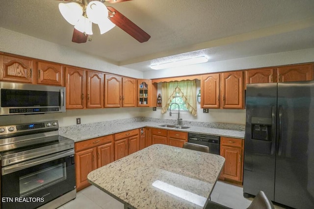 1301 Chert Pit Rd, Knoxville, TN 37923 - kitchen with appliances with stainless steel finishes, brown cabinets, light stone countertops, a ceiling fan, and a textured ceiling