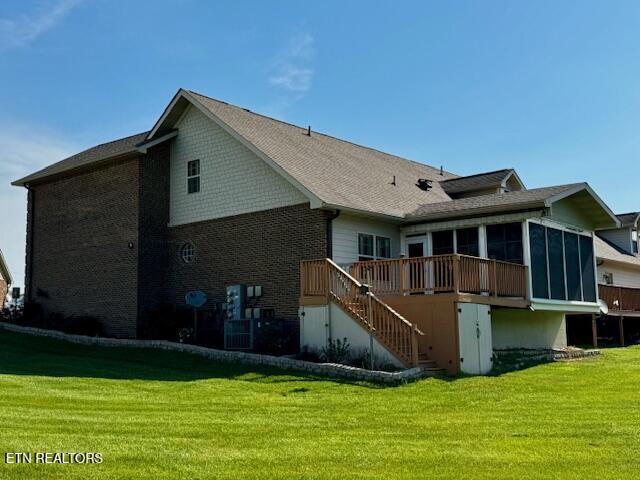 back of house featuring a sunroom, stairs, a wooden deck, and a lawn