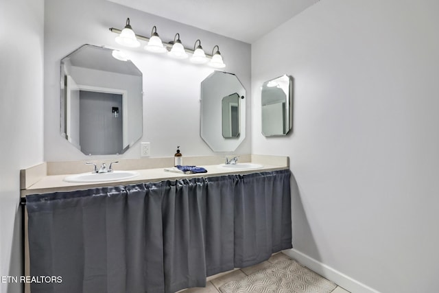 bathroom featuring tile patterned flooring, double vanity, baseboards, and a sink