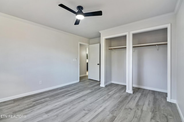 unfurnished bedroom with wood finished floors, baseboards, two closets, and ornamental molding