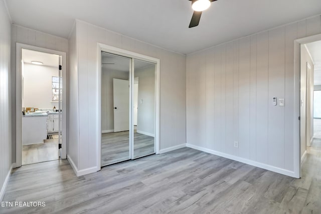 unfurnished bedroom with a closet, baseboards, a ceiling fan, and wood finished floors