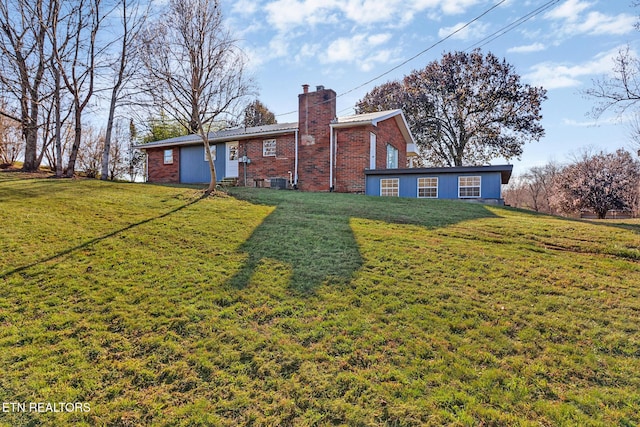 rear view of house featuring a yard, brick siding, cooling unit, and a chimney