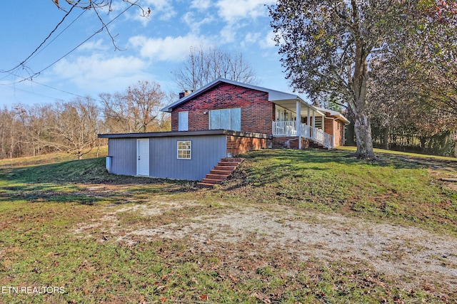 exterior space featuring a front lawn, stairway, covered porch, brick siding, and a chimney