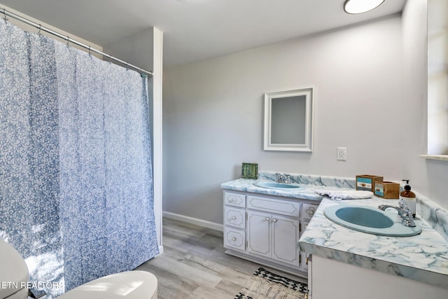 bathroom featuring toilet, vanity, baseboards, and wood finished floors