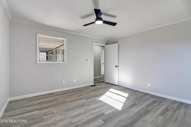 unfurnished bedroom with visible vents, ornamental molding, baseboards, and wood finished floors