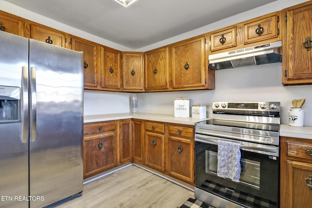 kitchen with under cabinet range hood, brown cabinetry, appliances with stainless steel finishes, and light countertops