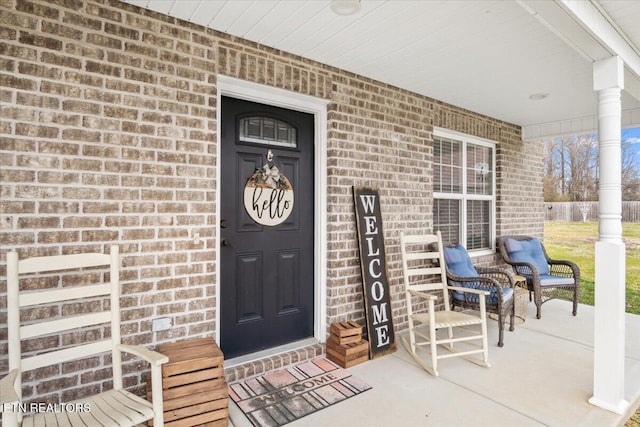 doorway to property featuring brick siding and covered porch