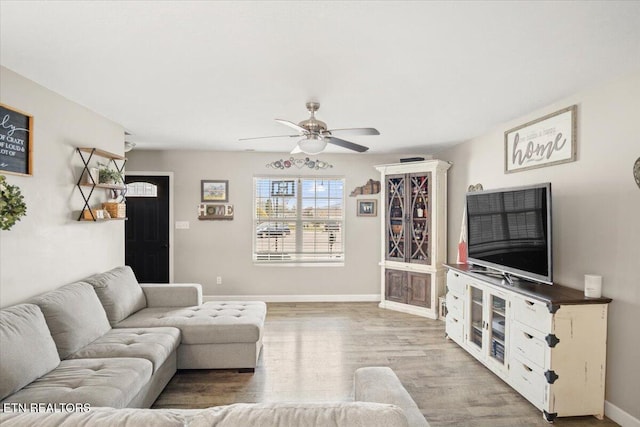 living room featuring baseboards, light wood finished floors, and ceiling fan