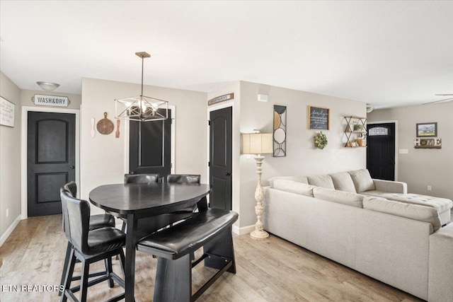 dining room featuring a notable chandelier, light wood-style floors, and baseboards