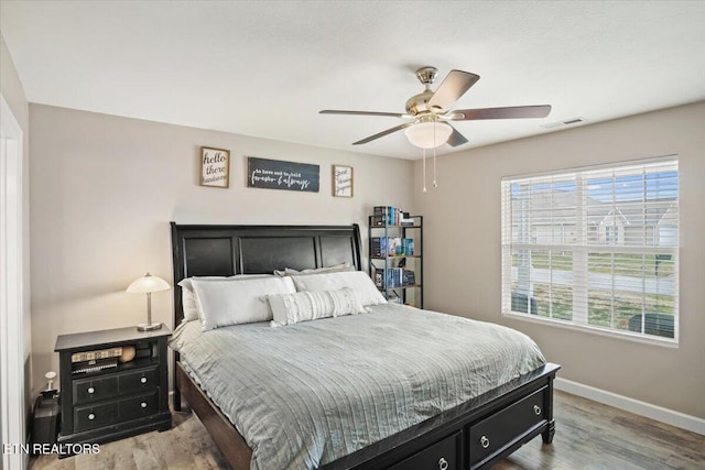 bedroom with visible vents, a ceiling fan, baseboards, and wood finished floors