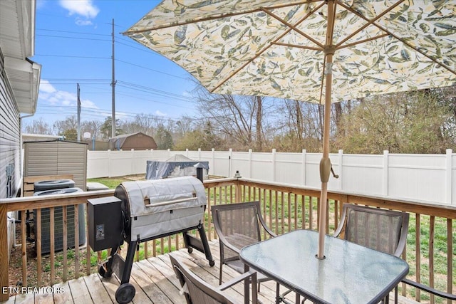 wooden terrace featuring grilling area, outdoor dining space, central air condition unit, and a fenced backyard