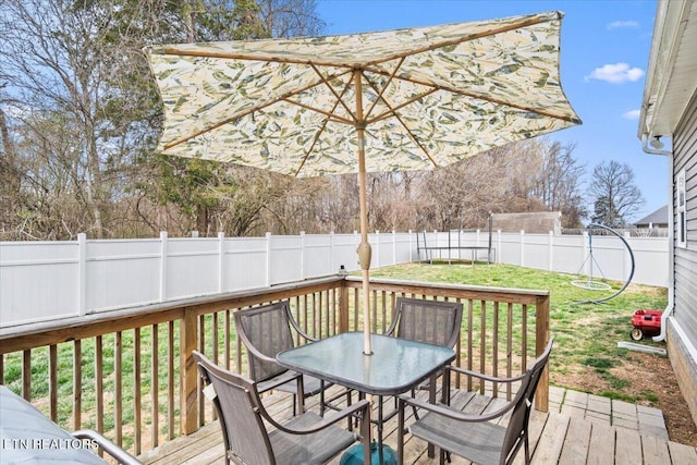 deck with outdoor dining space, a lawn, and a fenced backyard