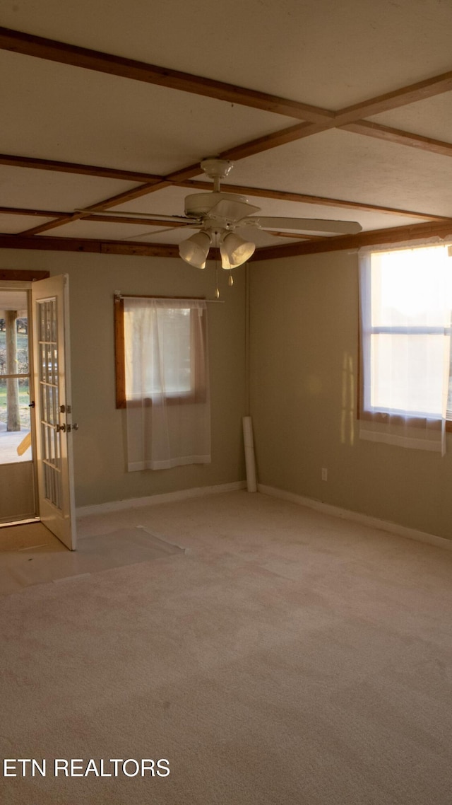 spare room featuring beam ceiling, light colored carpet, baseboards, and ceiling fan