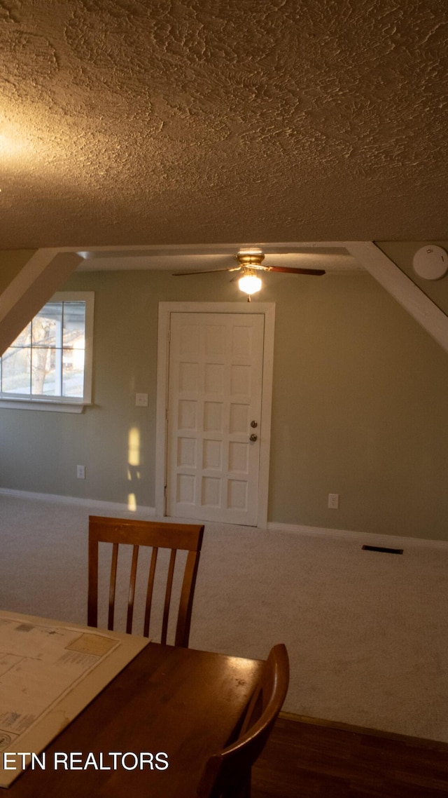 unfurnished dining area featuring baseboards, a textured ceiling, ceiling fan, and carpet flooring