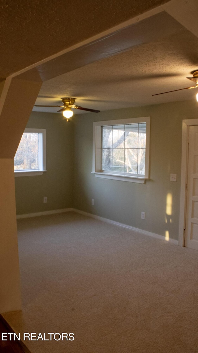 carpeted empty room featuring a textured ceiling, baseboards, and ceiling fan