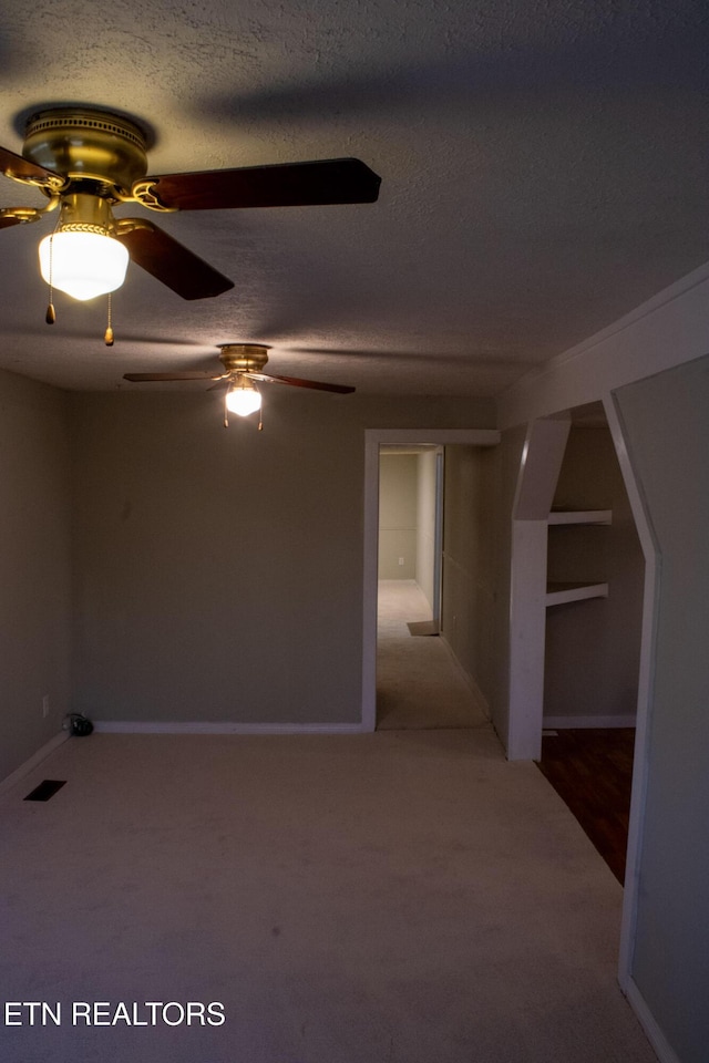 carpeted empty room with a ceiling fan, visible vents, and a textured ceiling