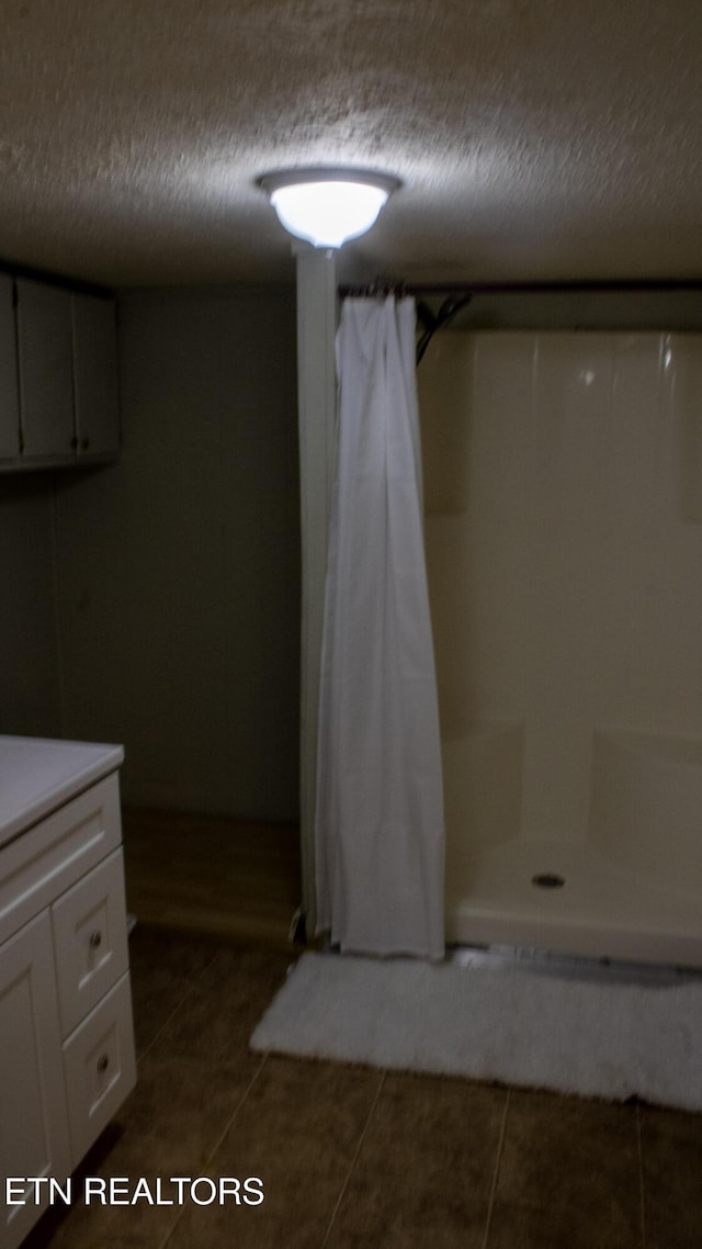 bathroom with tile patterned flooring, curtained shower, and a textured ceiling