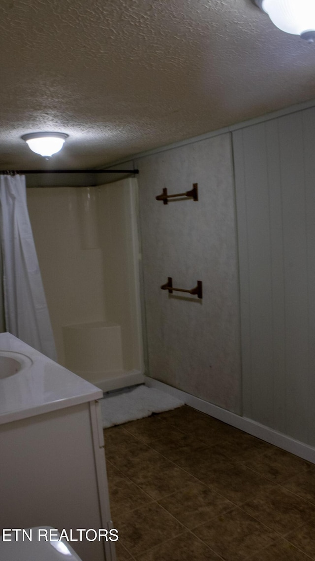 bathroom with tile patterned floors, a textured ceiling, and vanity