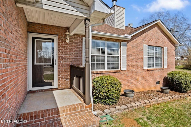 property entrance with crawl space, brick siding, and a chimney