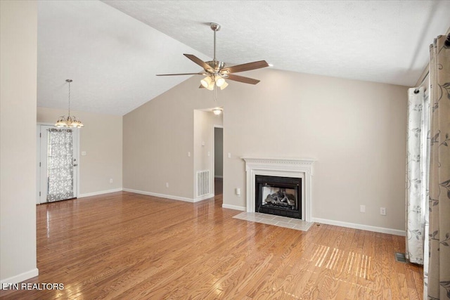 unfurnished living room featuring light wood-style floors, a fireplace with flush hearth, ceiling fan with notable chandelier, and visible vents