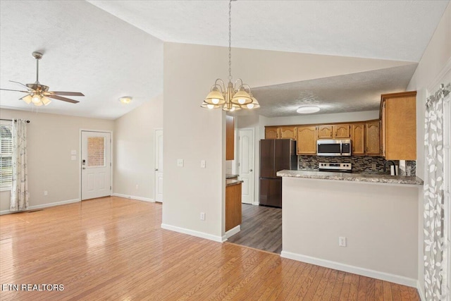 kitchen featuring lofted ceiling, appliances with stainless steel finishes, light wood-style flooring, and brown cabinets