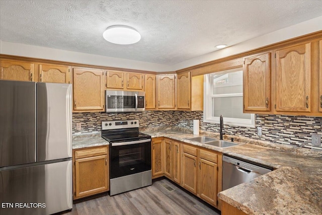 kitchen with a sink, decorative backsplash, dark wood-type flooring, stainless steel appliances, and a textured ceiling