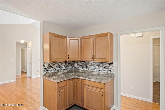 kitchen with decorative backsplash, light wood-style floors, and baseboards